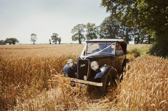 A beautiful bride in her 1950s wedding dress tieing the knot rustic style on a Cornfield on her home farm in Somerset